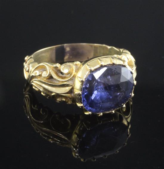 An antique yellow metal ring set with an oval sapphire in scroll-carved and pierced mount, size O.